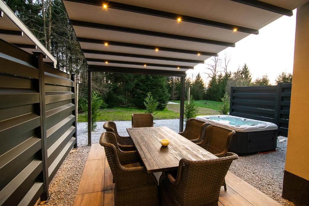 The pergola terrace at dusk — wicker dining set under warm lights, the hot tub to the side