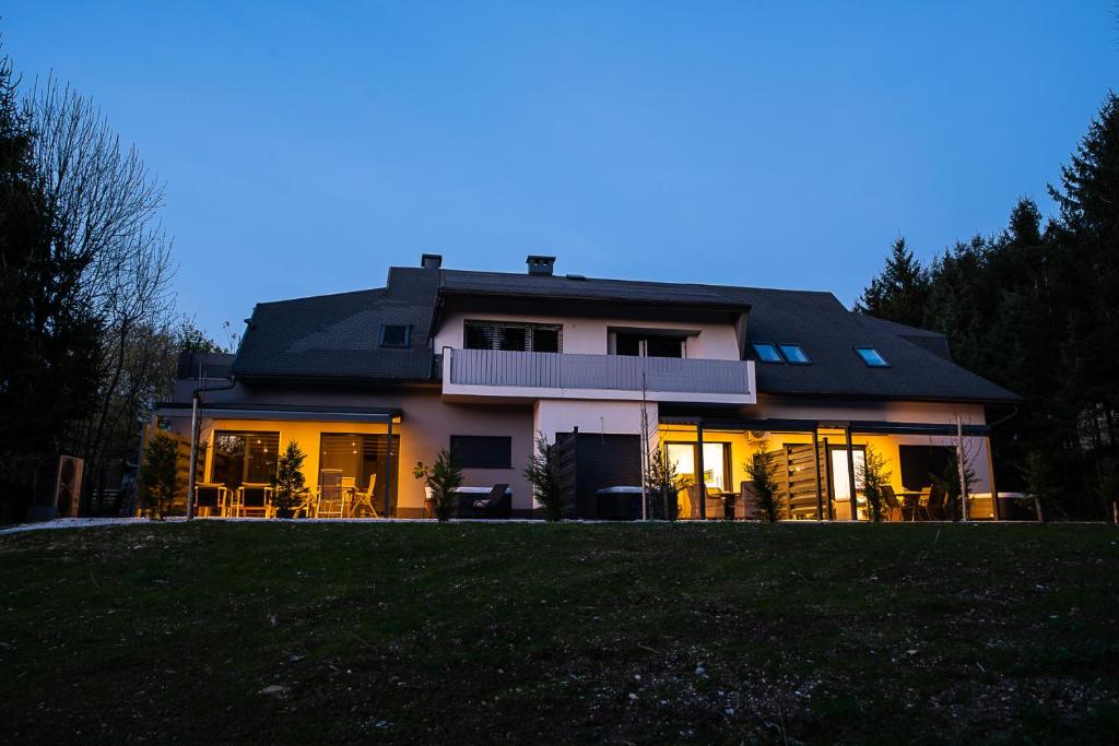The villa at blue hour, glowing warm through the trees