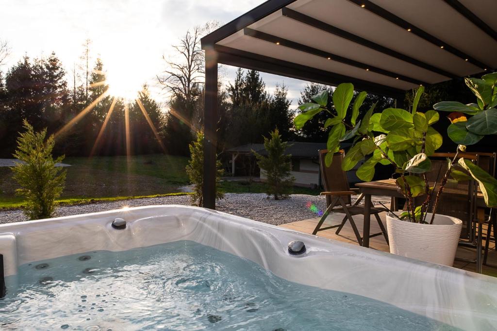 The hot tub on a private terrace in daylight, the sun bursting through tall trees onto the water
