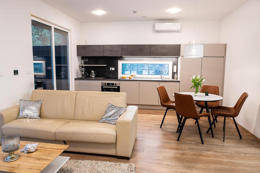 Open-plan living room of a Deluxe apartment — cream sofa, dining table with tulips, kitchen behind